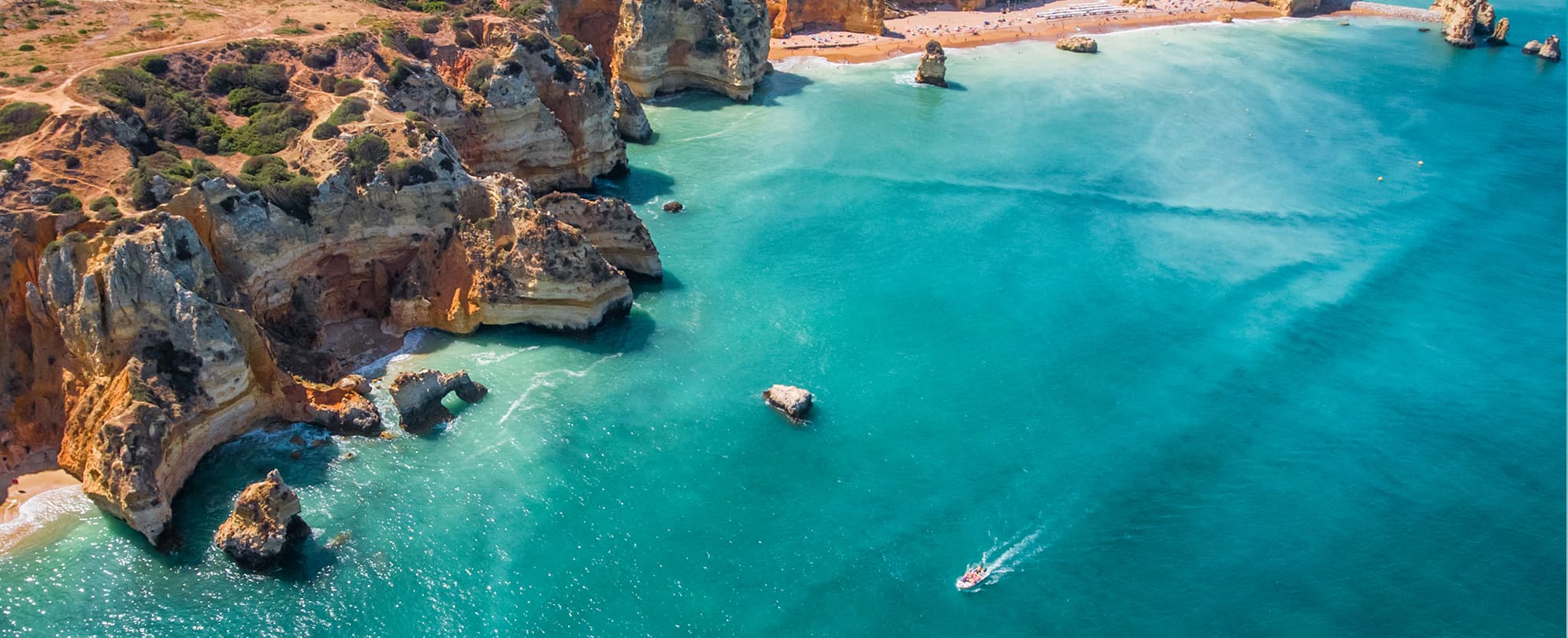 Speed boat in the ocean driving by large cliff formations 