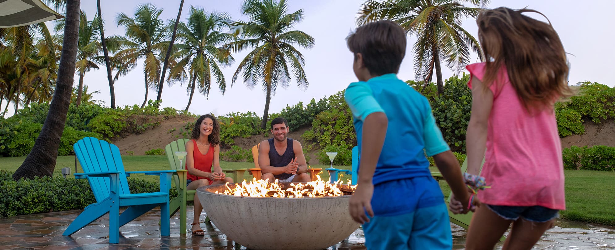 Family of four gathering around a fire pit 